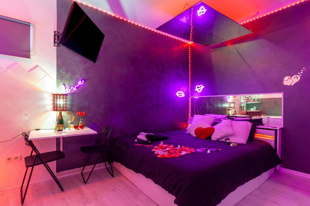 a purple bedroom with a bed and a desk and lights at Love Room avec Balnéo in Toulon