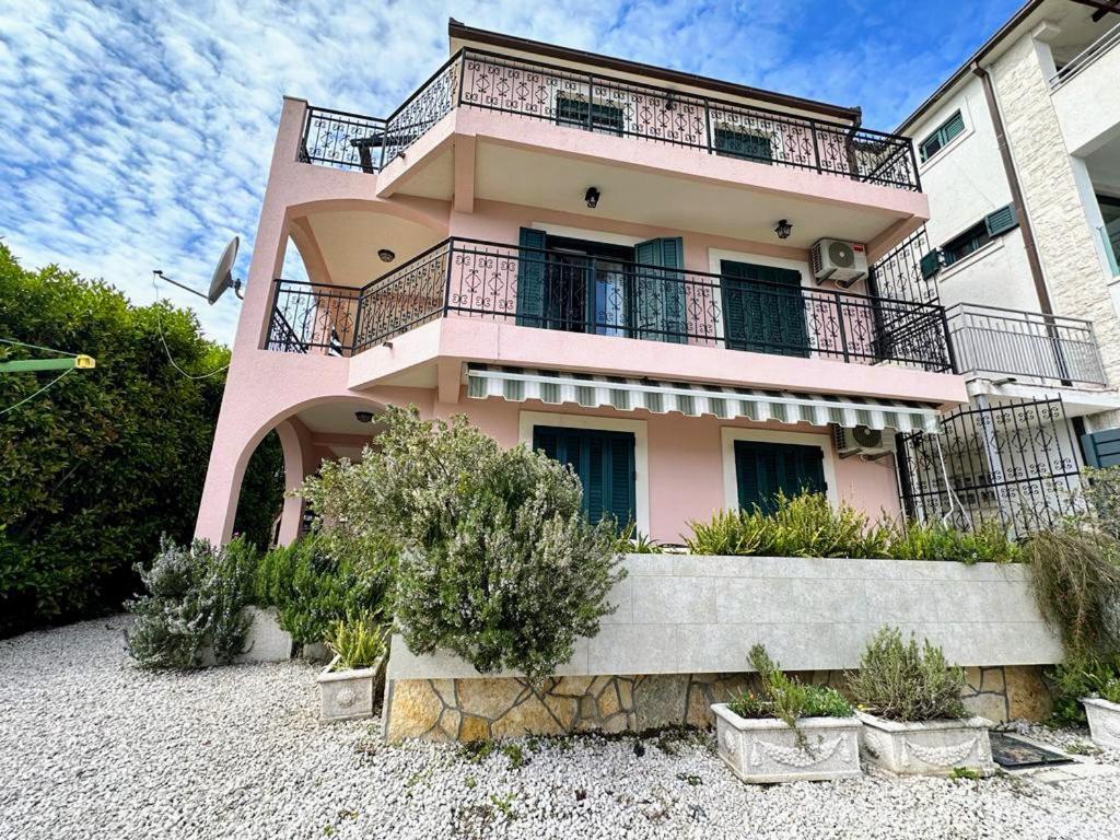 ein rosafarbenes Haus mit Balkon darüber in der Unterkunft Monteview Duplex in Herceg-Novi