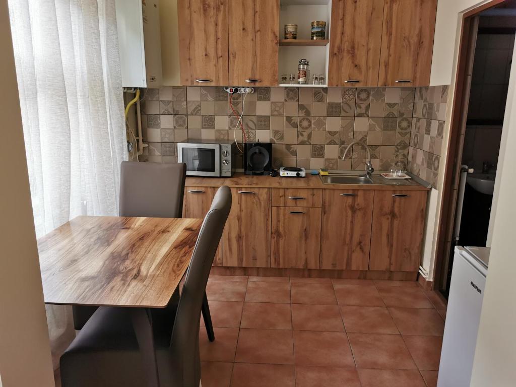 a kitchen with a wooden table and a microwave at APARTAMENT REGUN in Reghin