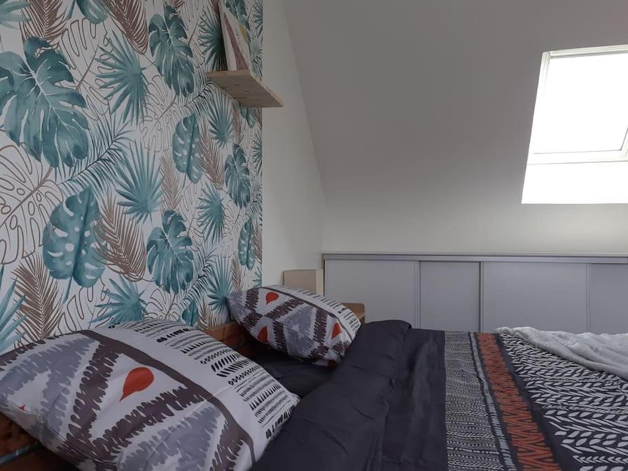 1 dormitorio con cama con almohadas y pared en L'artistique, 4 lits, 2 chambres, spacieux, atypique, en Amiens