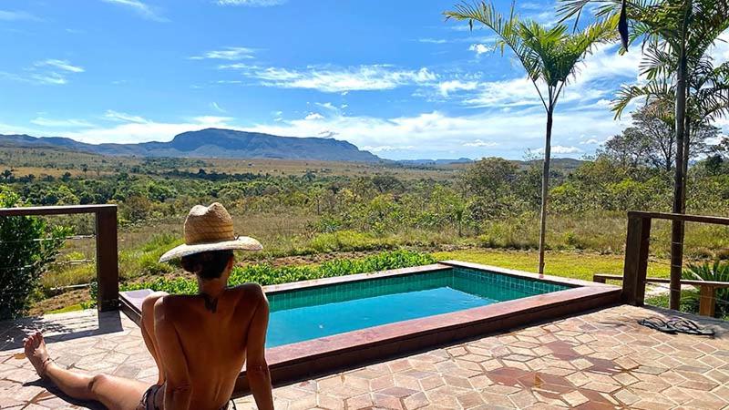 a woman in a hat sitting next to a swimming pool at Sítio São Chico in Alto Paraíso de Goiás