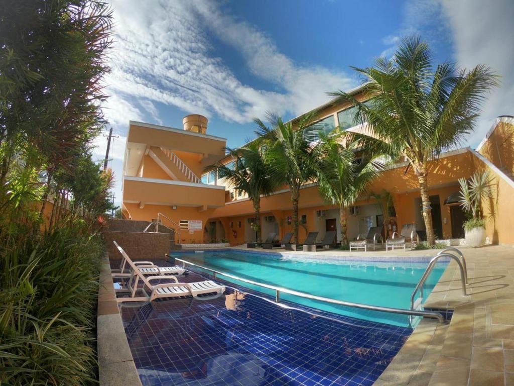 a house with a swimming pool and palm trees at Pousada Atlantic Sun in Bertioga