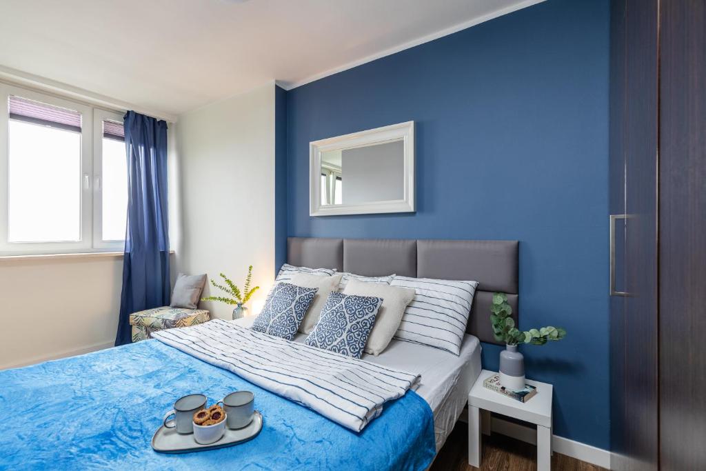 Un dormitorio azul con una cama con una bandeja de comida. en SuperApart Etiudy Rewolucyjnej 9, en Varsovia