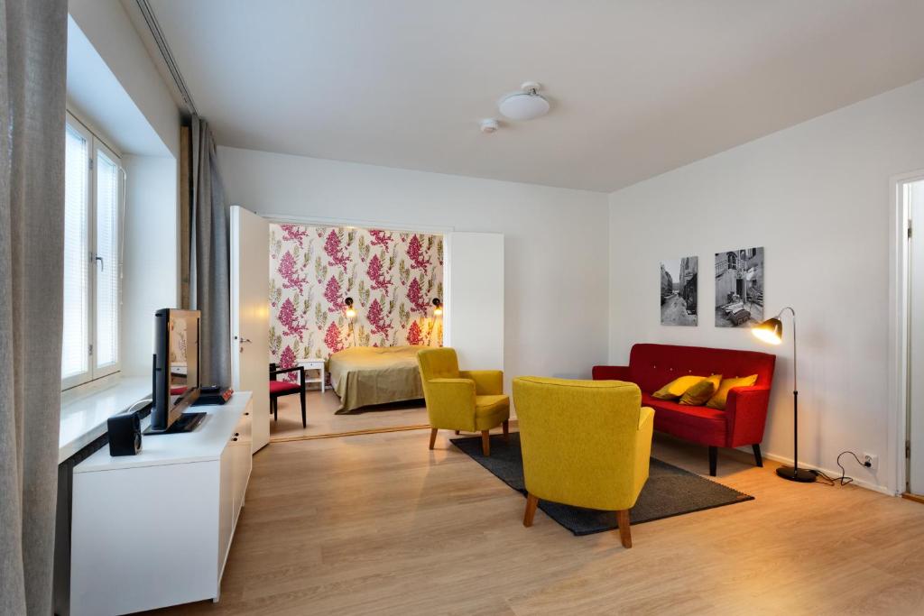 een woonkamer met een rode bank en gele stoelen bij Forenom Serviced Apartments Helsinki Kruununhaka in Helsinki