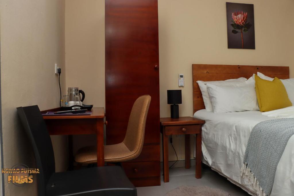 1 dormitorio con 1 cama y escritorio con silla en The Hill Bed and Breakfast, en Francistown