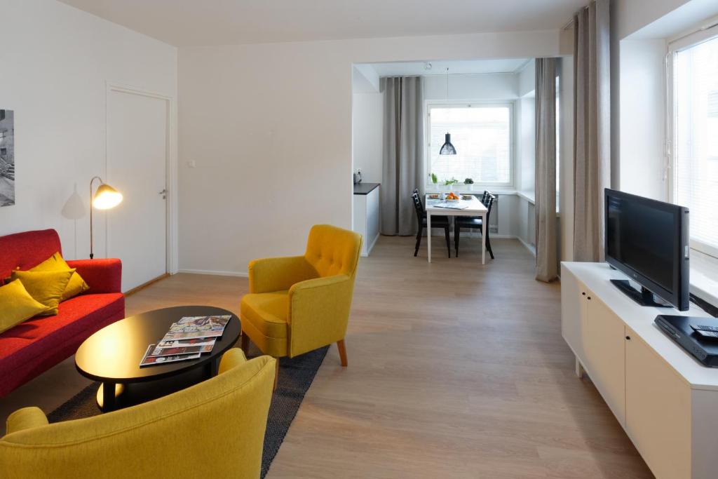 a living room with a red couch and yellow chairs at Forenom Serviced Apartments Helsinki Kruununhaka in Helsinki