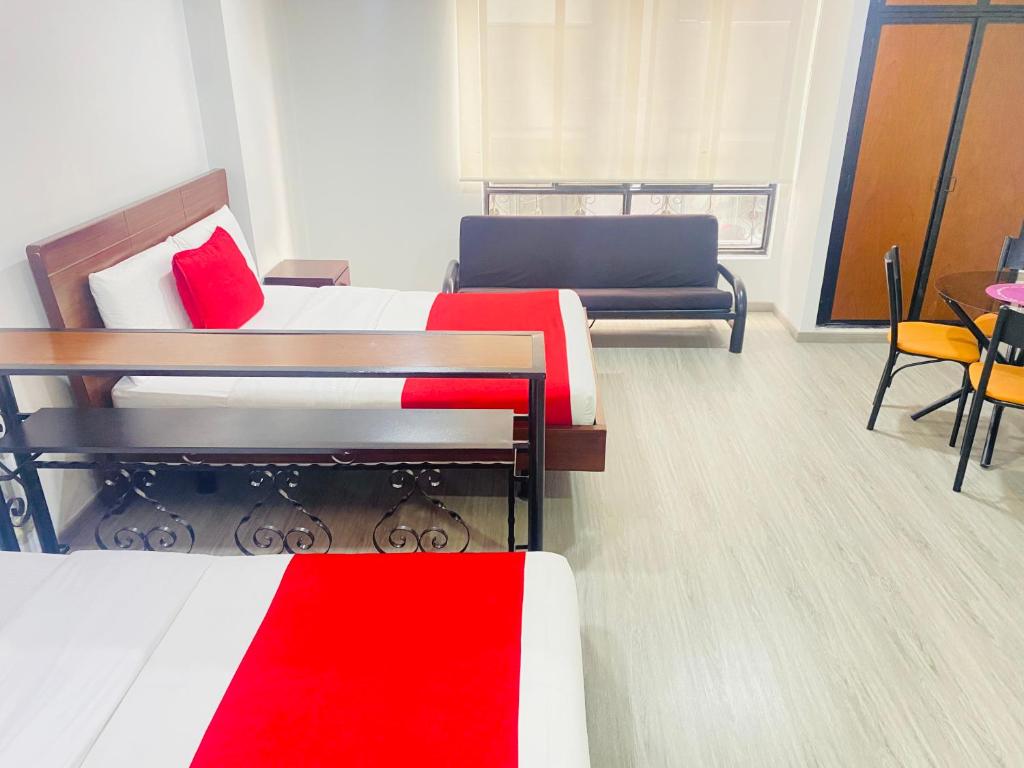 Cette chambre comprend deux lits, une table et des chaises. dans l'établissement APARTAESTUDIO AMOBLADO DE UN SOLO AMBIENTE- QUINTA PAREDES CORFERIAS, à Bogotá