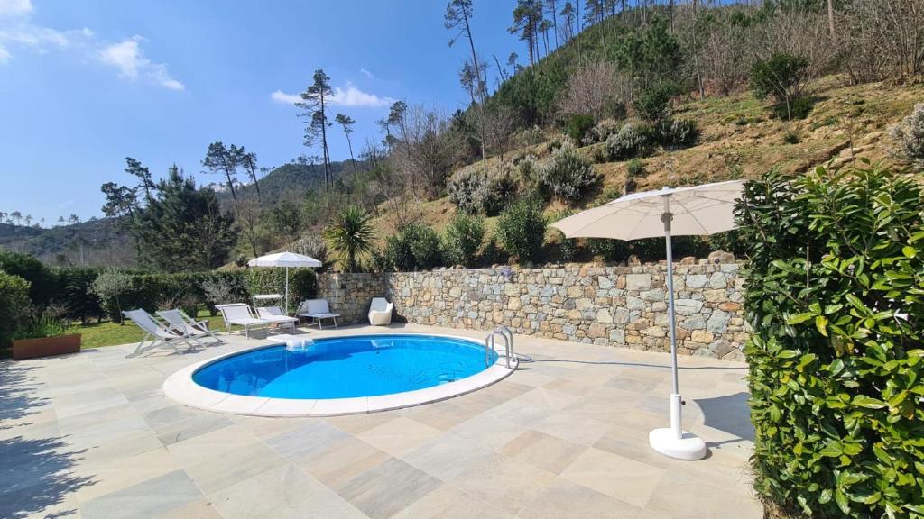 una piscina con sombrilla junto a una pared de piedra en Orchidea en Beverino