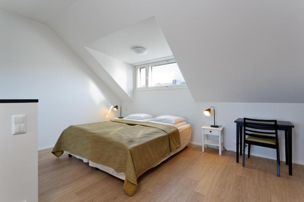 a white bedroom with a bed and a chair at Forenom Serviced Apartments Helsinki Kruununhaka in Helsinki