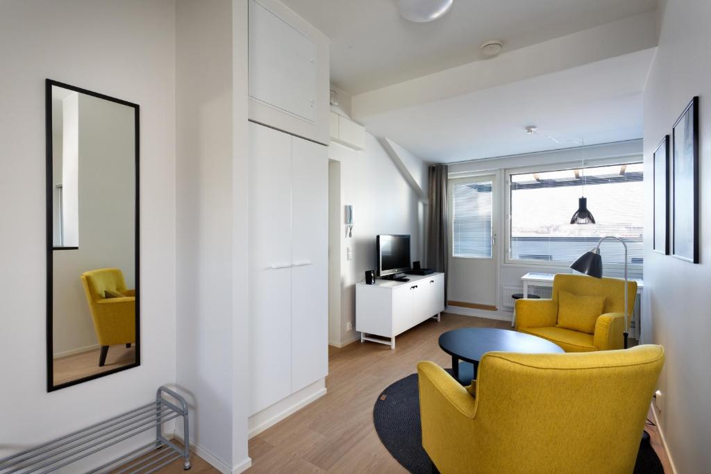 a living room with yellow chairs and a table at Forenom Serviced Apartments Helsinki Kruununhaka in Helsinki