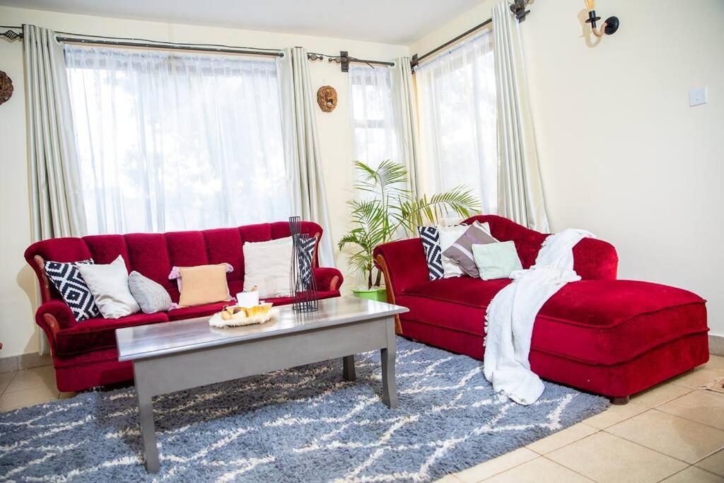 Sala de estar con 2 sofás rojos y mesa de centro en The White Dove - At Migaa Golf Estate en Kiambu