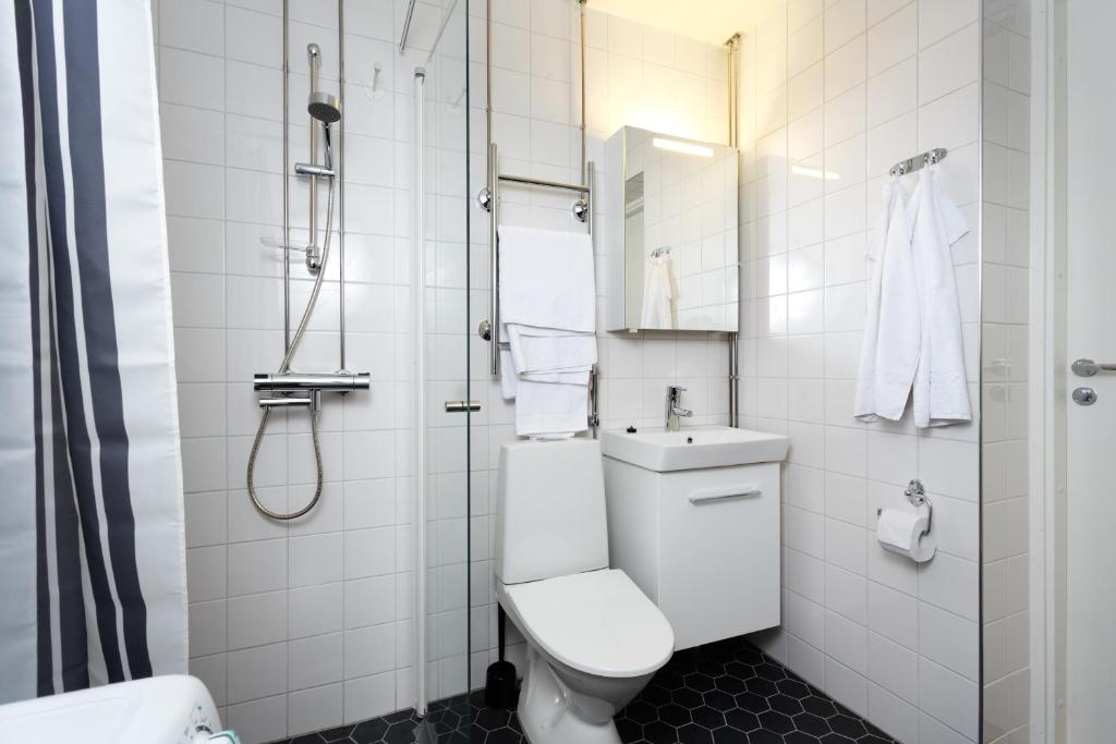 a white bathroom with a toilet and a shower at Forenom Serviced Apartments Helsinki Kruununhaka in Helsinki