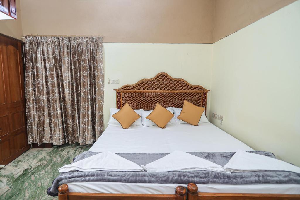 NALINAM HOMESTAY في تريفاندروم: غرفة نوم مع سرير مع وسائد برتقالية