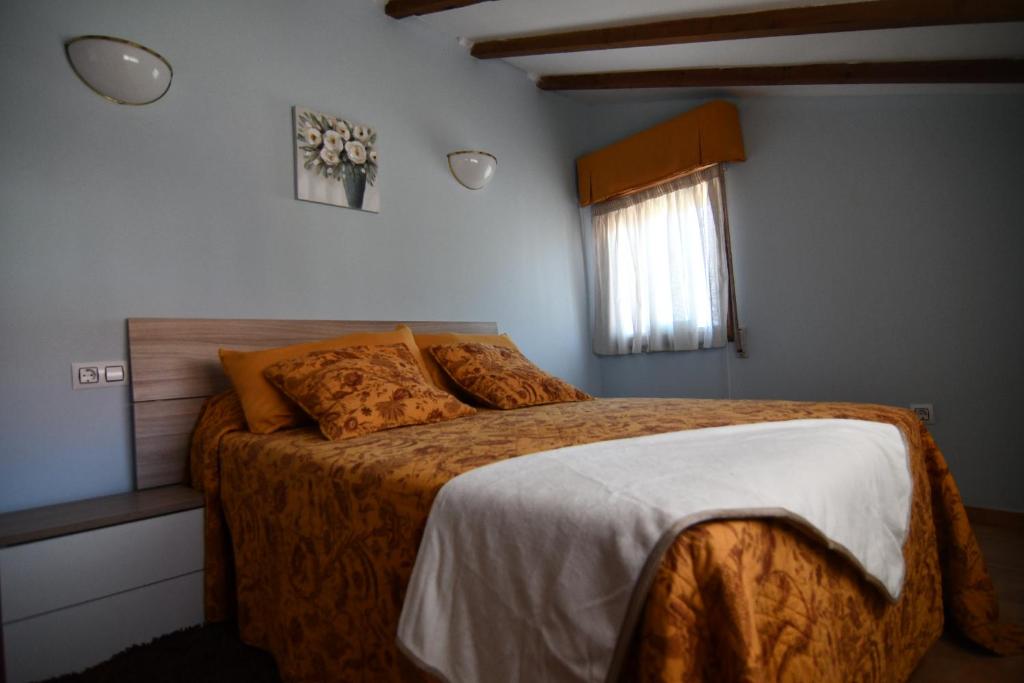 een slaapkamer met een bed met oranje lakens en een raam bij Casa Avoa María in Ourense