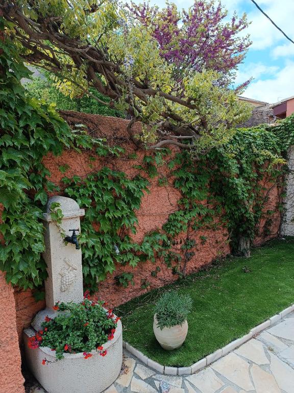 a garden with two pots of plants next to a brick wall at Aux Berges du Canal in Capestang