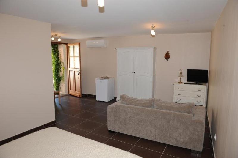 a living room with a couch and a television at Aux Berges du Canal in Capestang