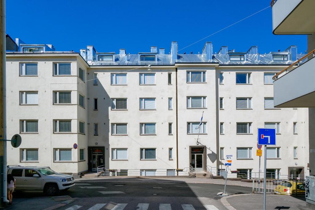 a large white building with a car parked in front of it at Forenom Serviced Apartments Helsinki Kruununhaka in Helsinki