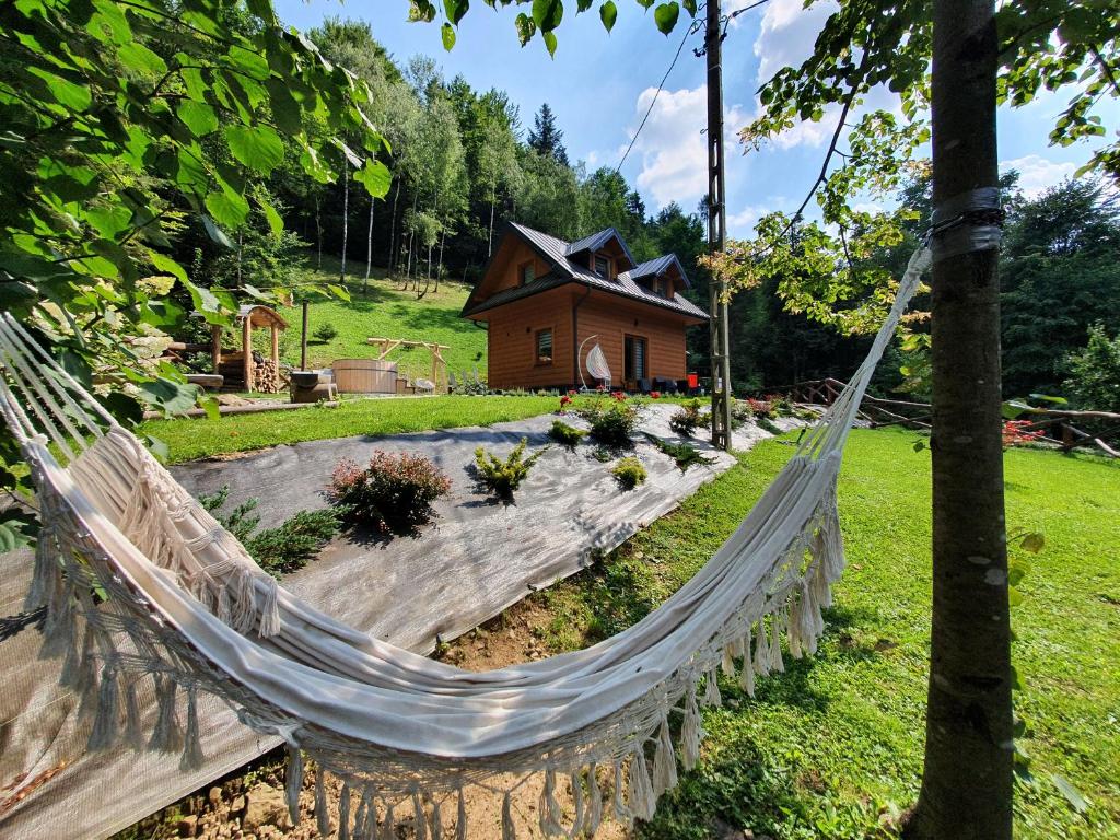 a hammock in a garden with a house in the background at Domek Nad Stawami Ochotnica Dolna in Ochotnica Dolna