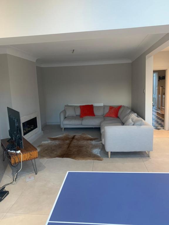 uma sala de estar com um sofá branco e uma televisão em 4 bedroomed luxury house in the heart of Beatles land em Childwall