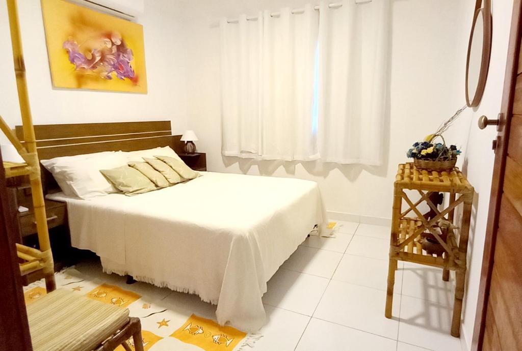um quarto com uma cama branca e uma janela em Chalé Jacu Beach em Pipa