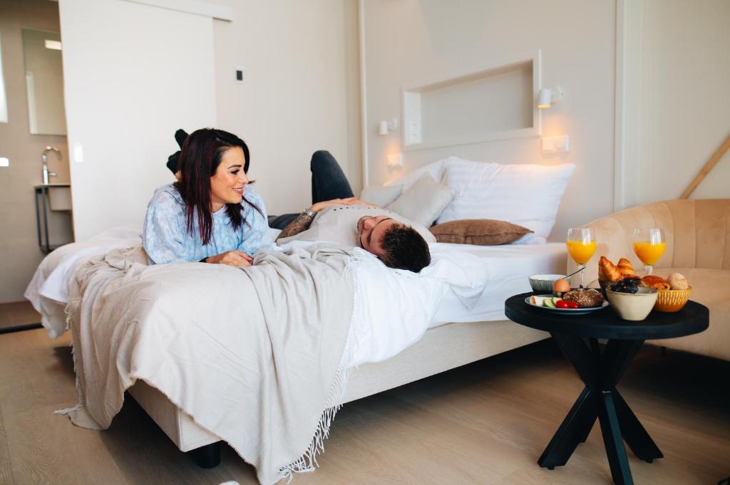 a woman laying on a bed next to a man at Hotel - B&B Renesse in Renesse