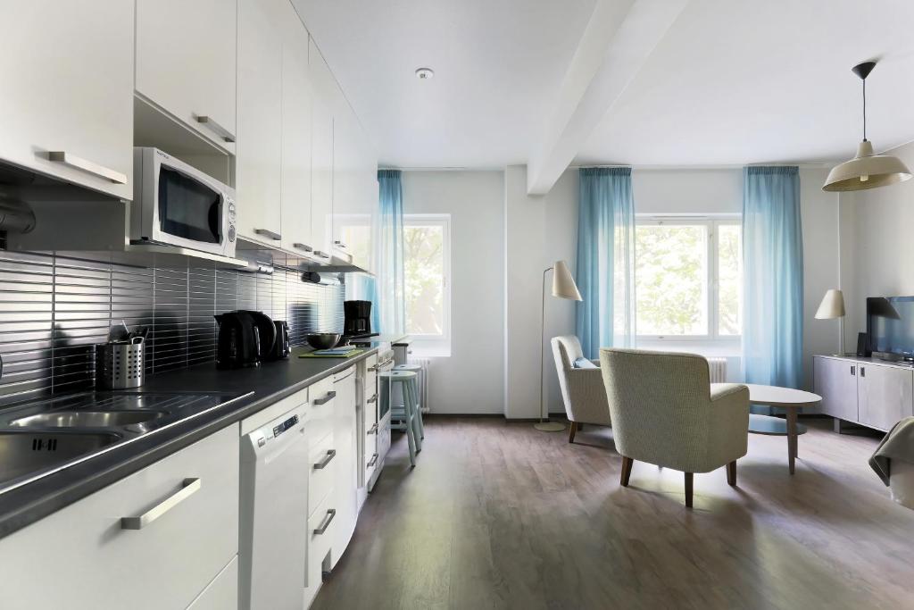 a kitchen with white cabinets and a table and chairs at Forenom Serviced Apartments Helsinki Lapinlahdenkatu in Helsinki