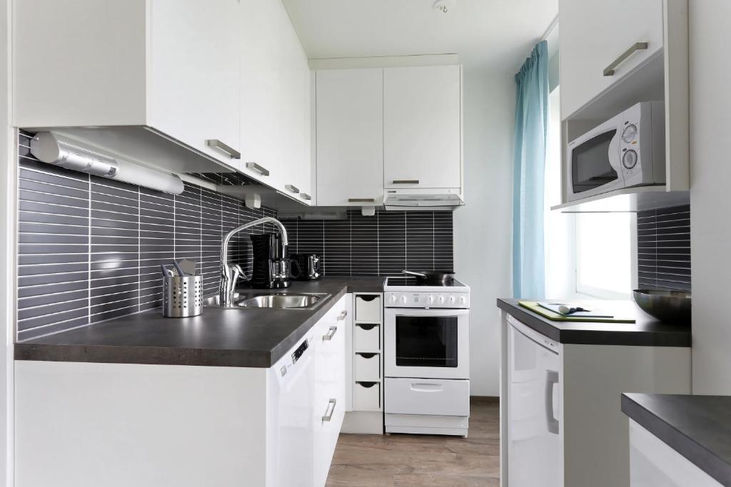 a kitchen with white cabinets and a sink at Forenom Serviced Apartments Helsinki Lapinlahdenkatu in Helsinki