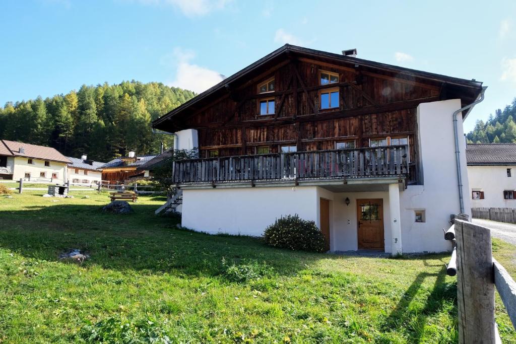 a wooden house with a balcony on a green field at Chasa Prümaran in Scuol
