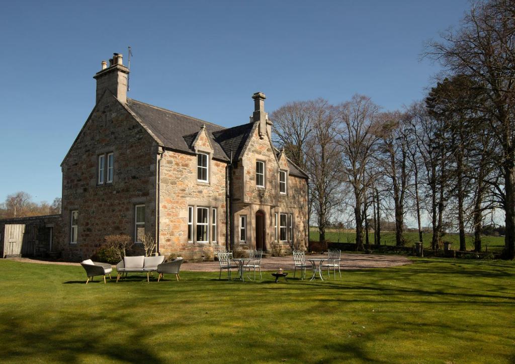 a large brick building with tables and chairs in front of it at Cardhu Country House in Aberlour