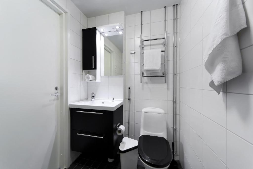 a white bathroom with a toilet and a sink at Forenom Serviced Apartments Helsinki Lapinlahdenkatu in Helsinki