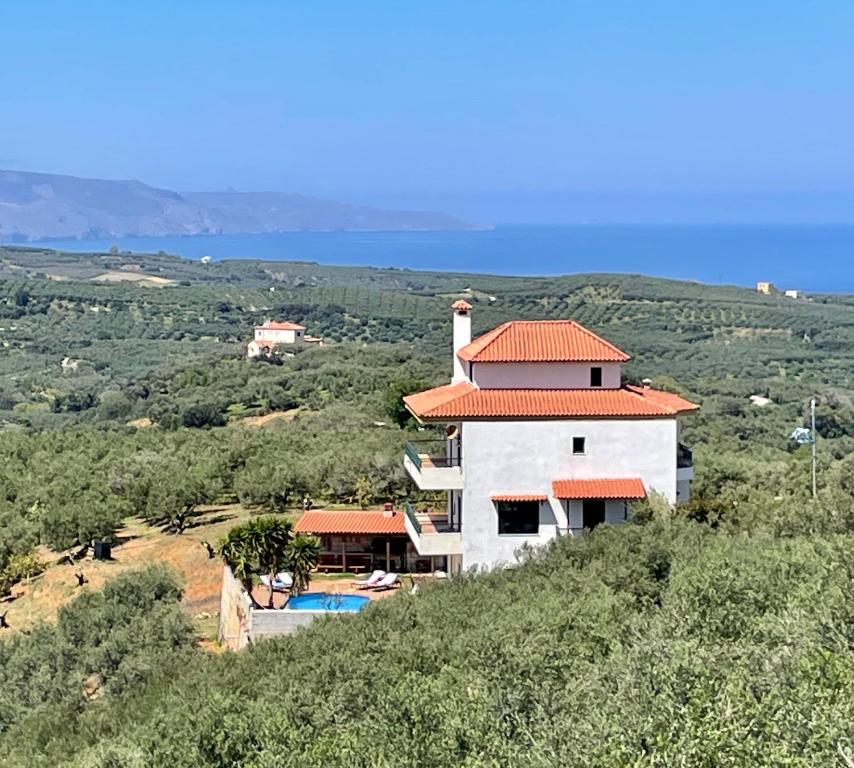 een gebouw met een oranje dak bovenop een heuvel bij Olive Villa in Xirokámbion