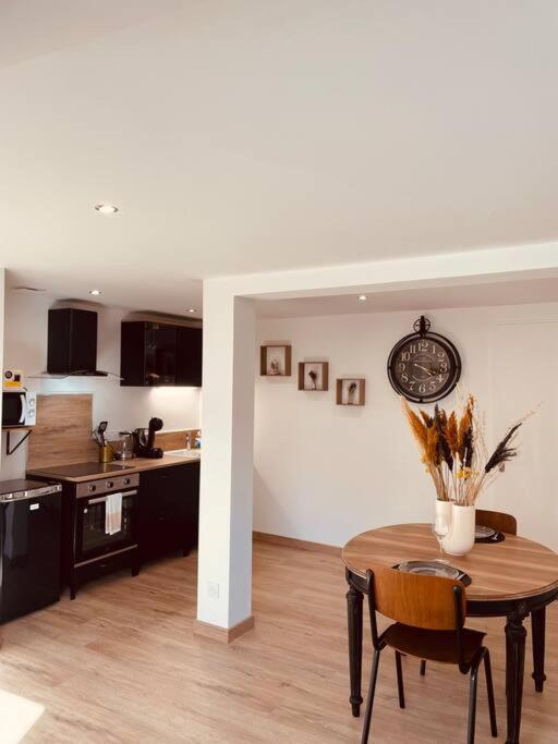 a kitchen with a table and a clock on the wall at Bryas 3 - Appartement très chaleureux in Châteauroux