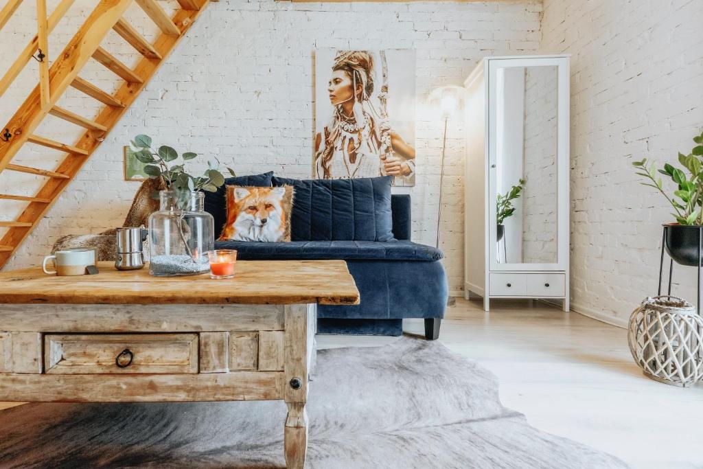 a living room with a blue couch and a wooden table at Apartament z antresolą in Okszów