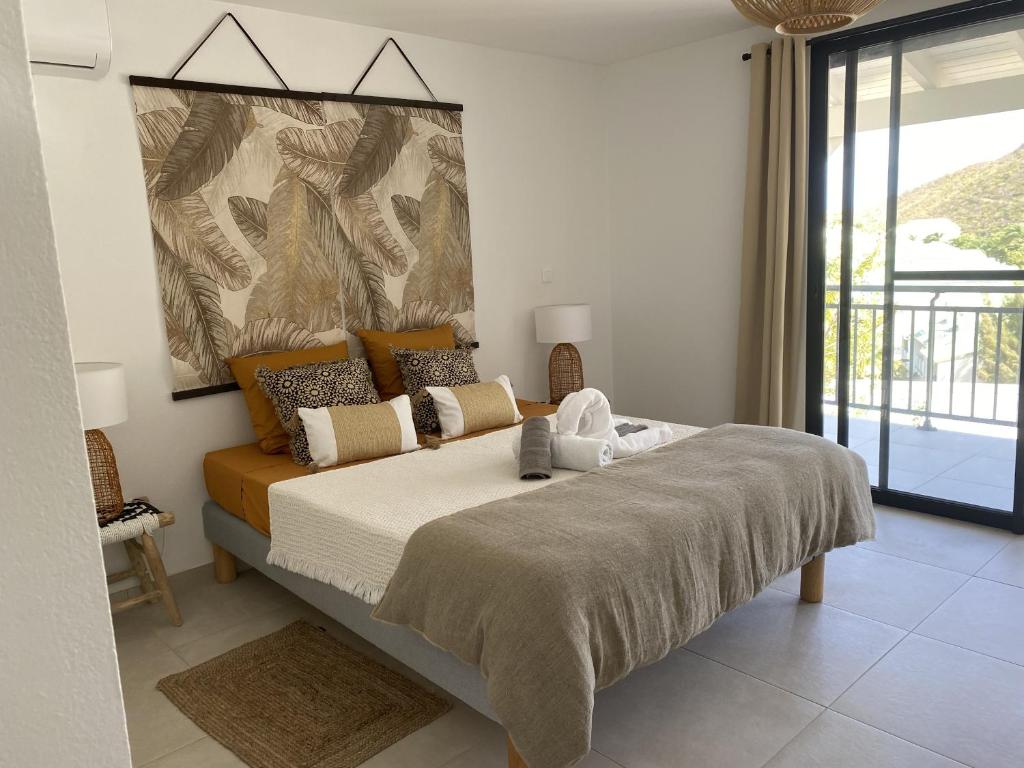 a bedroom with a large bed and a large window at Cottage Cosy Duplex Anse Marcel, Vue mer et marina in Anse Marcel 