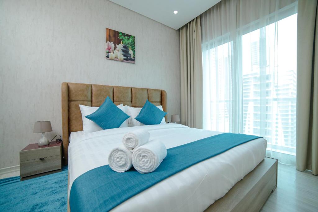 Vita Suites في المنامة: غرفة نوم بسرير كبير ومخدات زرقاء وبيضاء