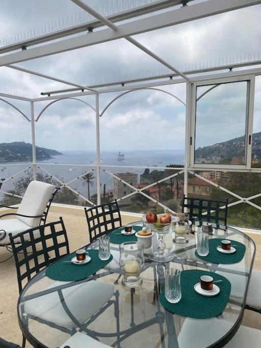 une table et des chaises en verre avec vue sur l'océan dans l'établissement Villa La Terrasse, à Villefranche-sur-Mer