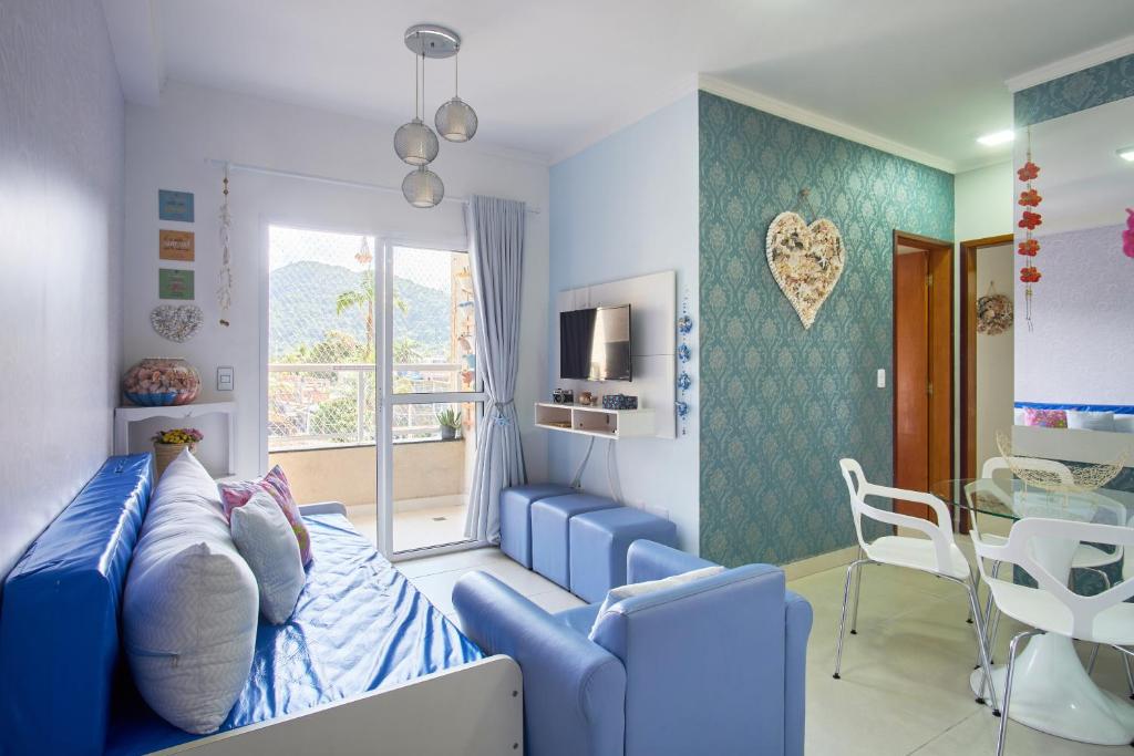 a room with a blue bed and a dining room at 2 Quartos com ar, piscina, sacada Gourmet a 1 km da praia Grande in Ubatuba