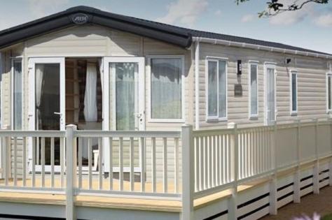 een wit huis met een veranda en een hek bij Hoburne Devon Bay Stunning 3 bed static caravan with full decking in Paignton