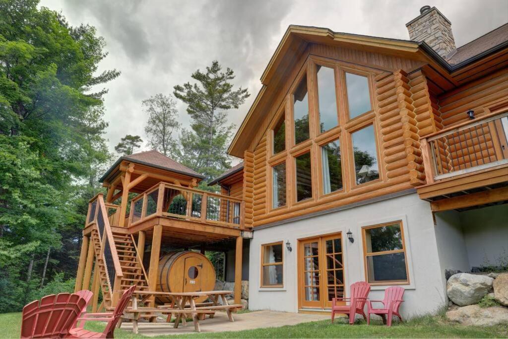 Casa de madera grande con terraza y sillas en Fiddler Lake Resort Chalet 96 Elk, en Mille-Isles