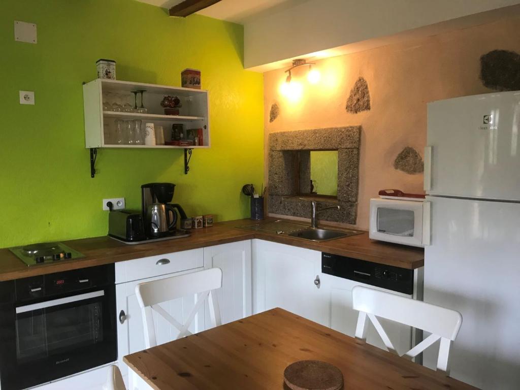 a kitchen with green walls and white cabinets and a white refrigerator at La Petite Finlande in Orbey