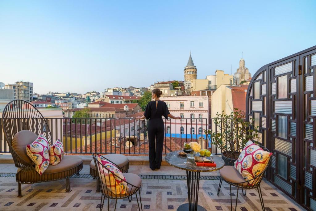 a woman standing on a balcony looking out at the city at The Galata Istanbul Hotel MGallery in Istanbul
