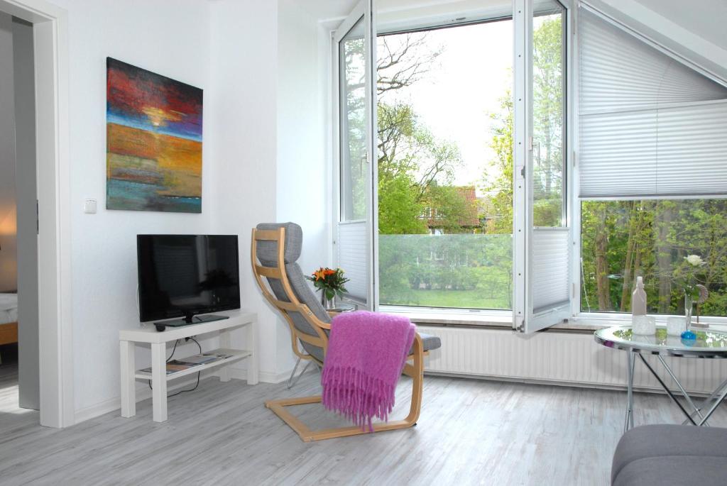 a living room with a chair and a tv at Seeschwalbe in Scharbeutz