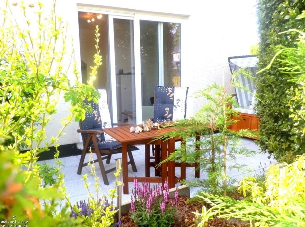 een patio met een houten tafel en stoelen op een veranda bij Käptns Koje in Wyk auf Föhr