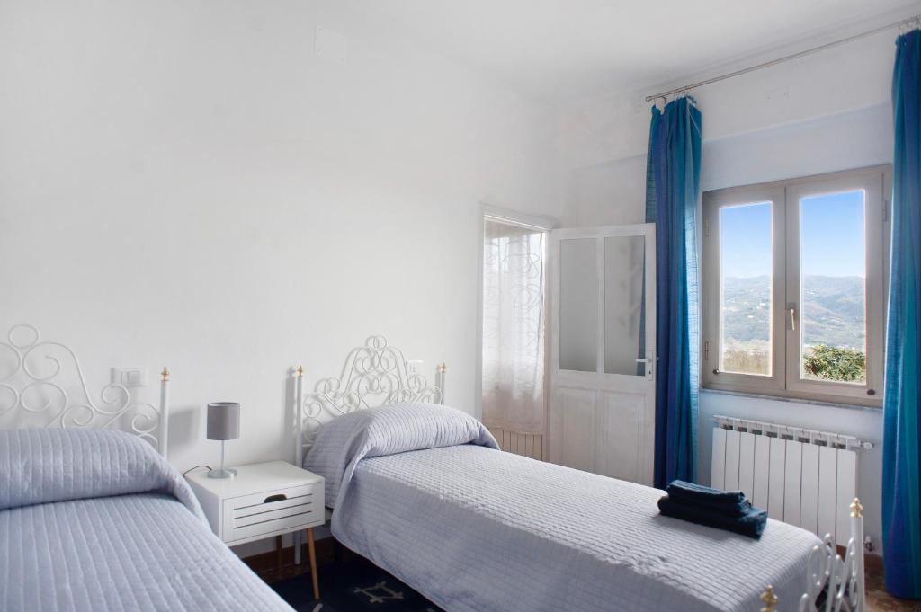 a bedroom with two beds with blue curtains and a window at Da Chicca in Bolano