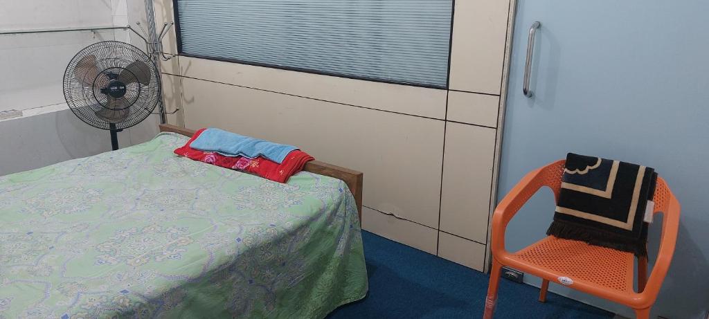 niewielka sypialnia z łóżkiem i krzesłem w obiekcie Kompass Homestay - Affordable AC Room With Shared Bathroom in Naya Paltan Free WIFI w mieście Dhaka