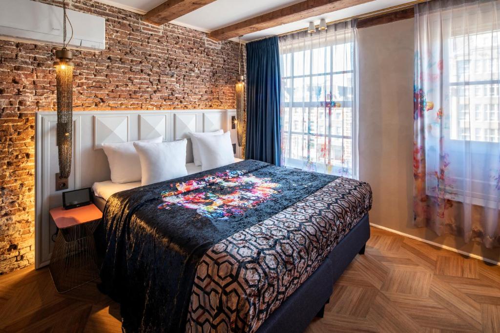 a bedroom with a bed and a brick wall at Mister Highland Hotel in Amsterdam