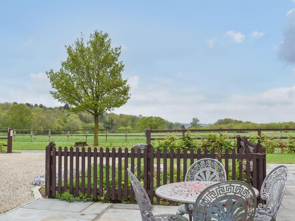 a table and chairs in front of a fence at Leveret Lodge in Leavenheath