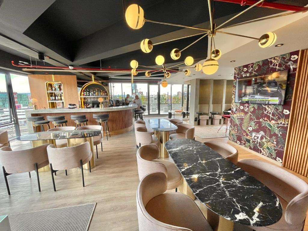 un restaurante con mesas y sillas y un bar en ICON 100 Luxury Apartasuites, en Bogotá