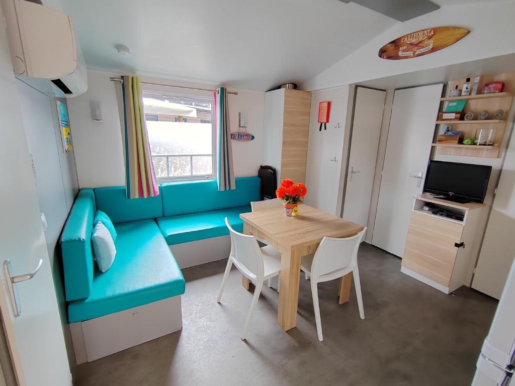 a small room with a table and a blue couch at Mobil home 6 Personnes au Atlantic Club Montalivet in Vendays-Montalivet