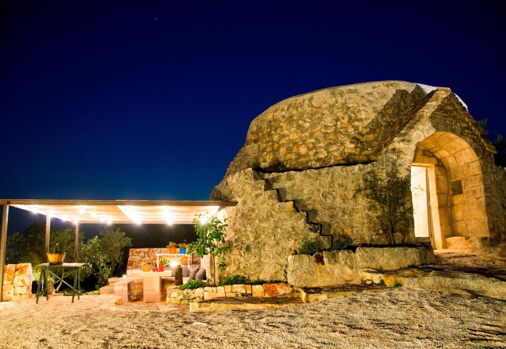 a stone building with a lit up door at night at Trullo fiore in Ostuni